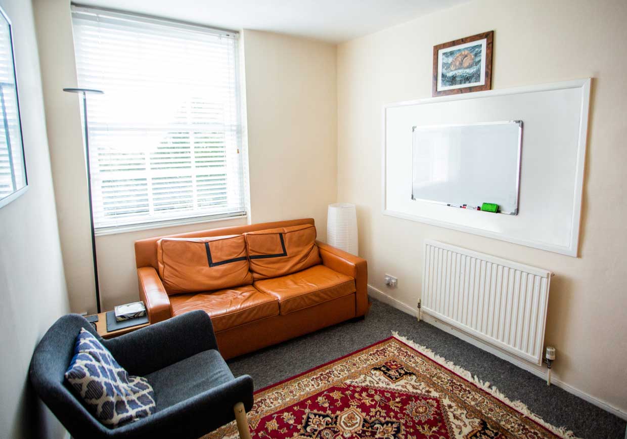 Room with a sofa, single seat, rug and a white board